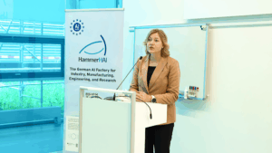 EU Commissioner Virkkunen talking at a podium at HLRS with a rollup with a HammerHAI logo in the background.