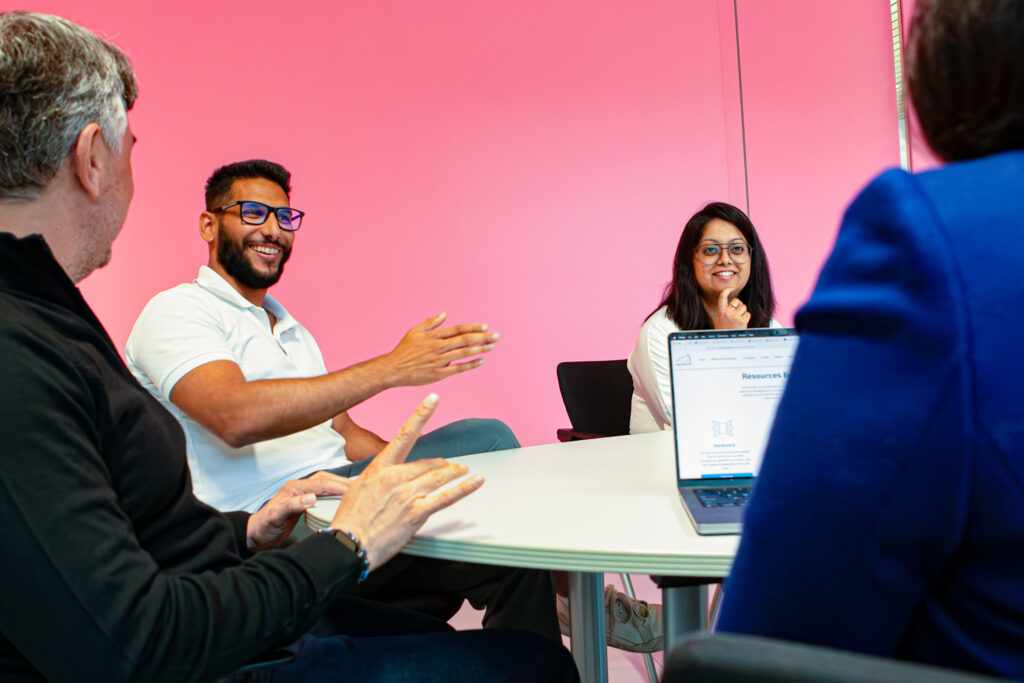 Four people discussing something at a table. One of them is gesticulating confidently.