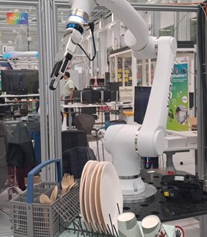 Picture showing a robotic arm in a production hall.